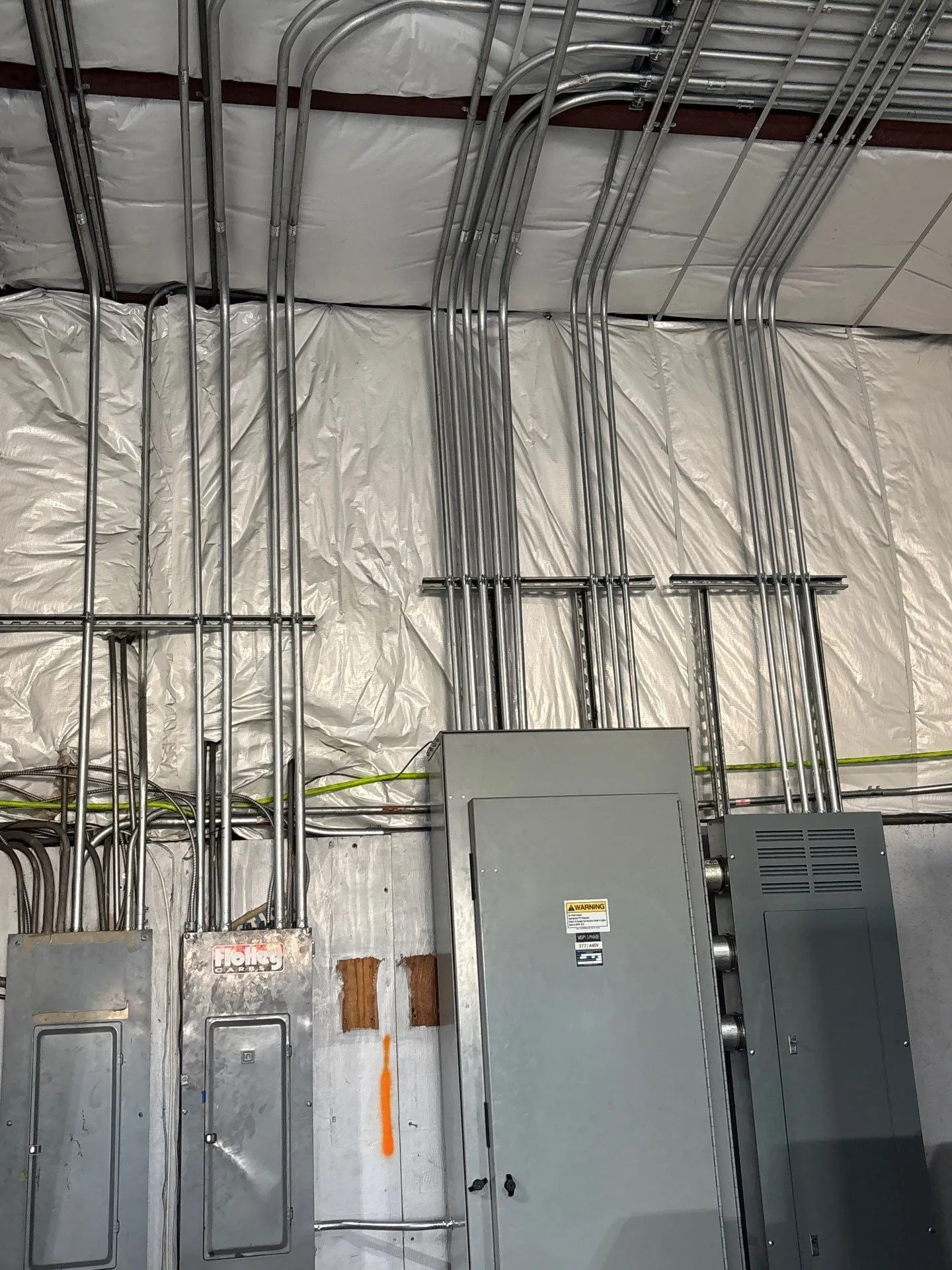 Bank of new electrical panels and conduit inside an industrial building