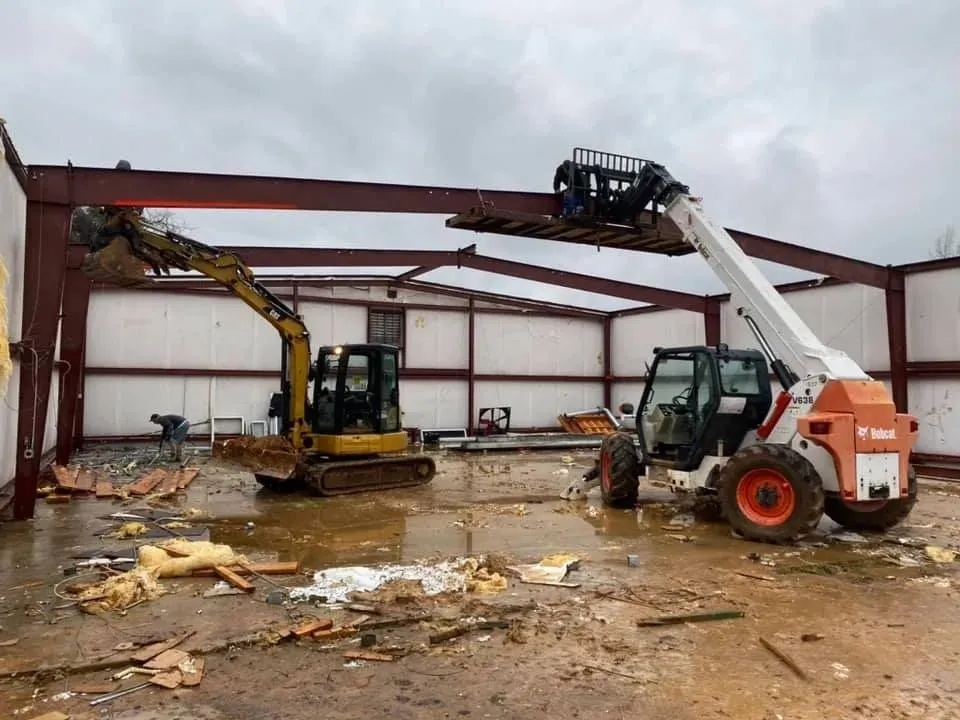 Red steel building frame going up with a telehandler lifting a beam