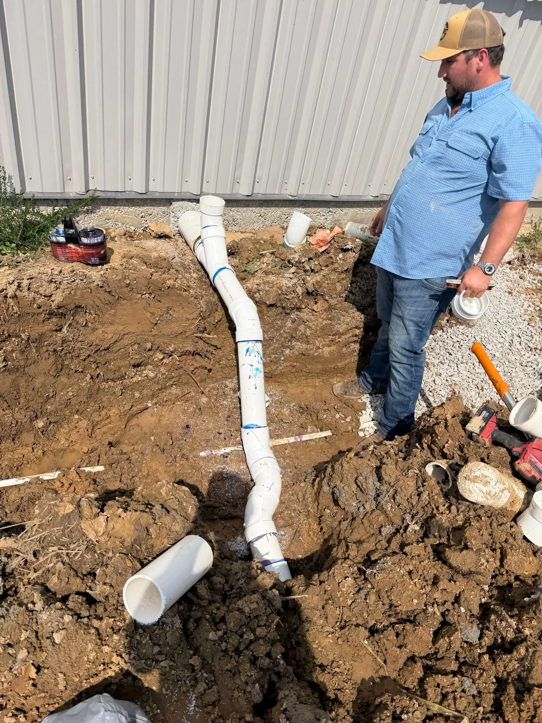 Plumbing lines being set in a trench beside the hangar
