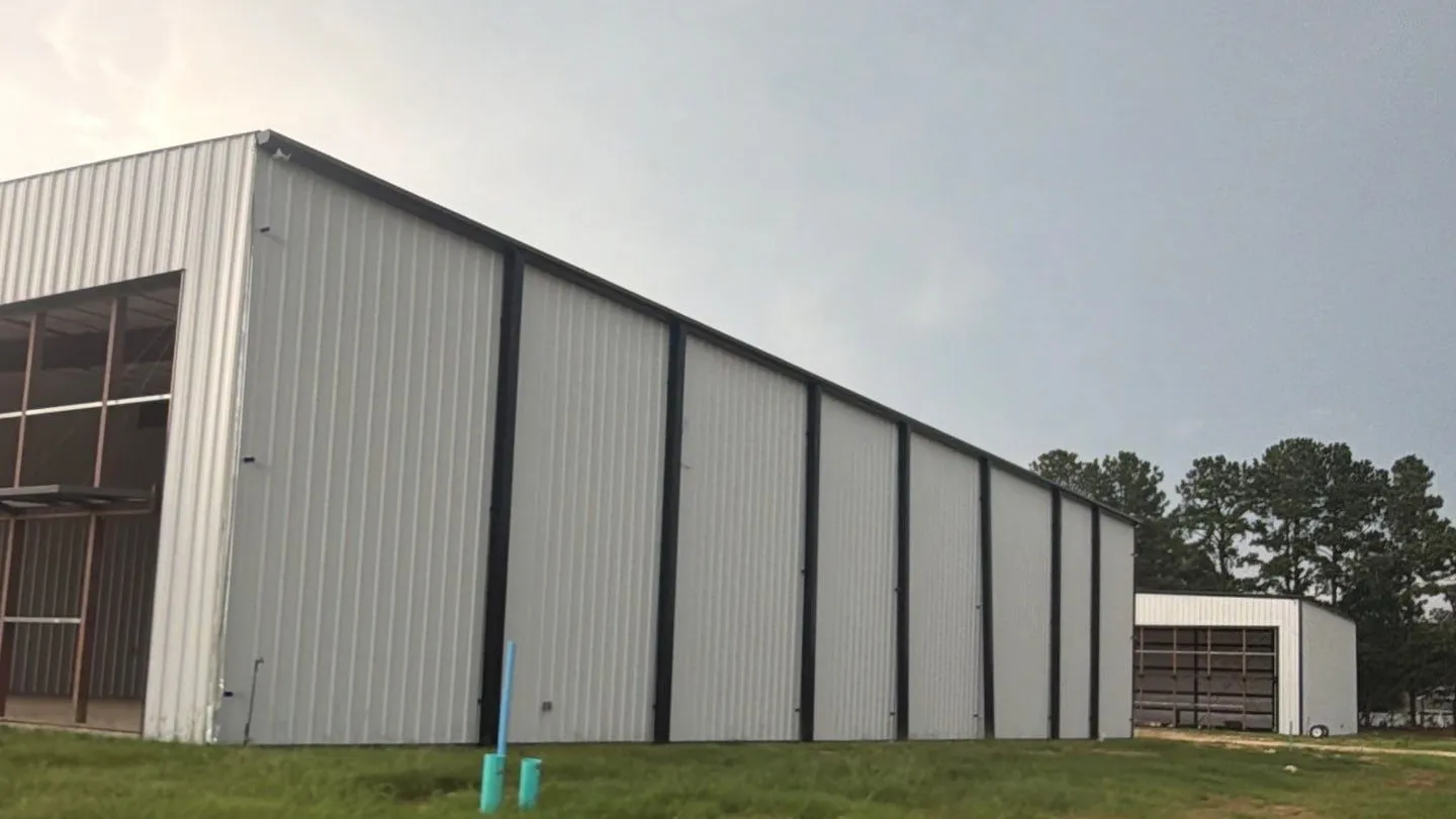 White steel hangar with black trim on a newly graded site