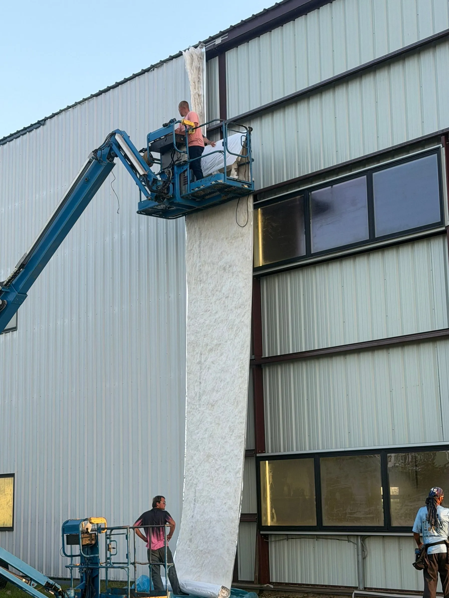 Crew on a boom lift setting windows in a hangar wall