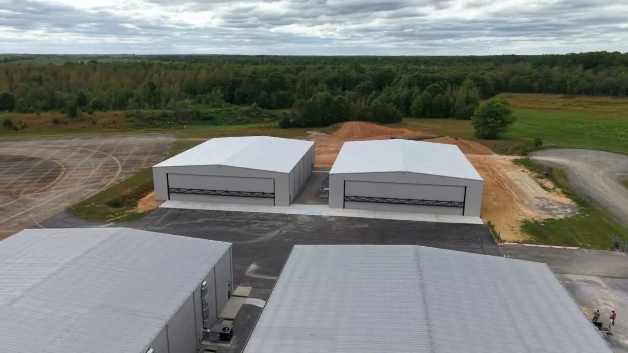 Aerial view of two new white steel hangars side by side on a fresh apron